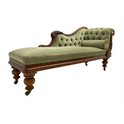 Victorian walnut framed chaise longue, the scrolled back carved with acanthus leaf and foliate motifs, the shaped rail applied with carved flower heads, upholstered in buttoned jade green fabric with bolter cushion, raised on turned supports with castors