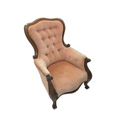 Victorian walnut framed armchair, shaped back with carved and scrolled arm terminals, upholstered in buttoned pale pink fabric, raised on cabriole supports terminating in castors