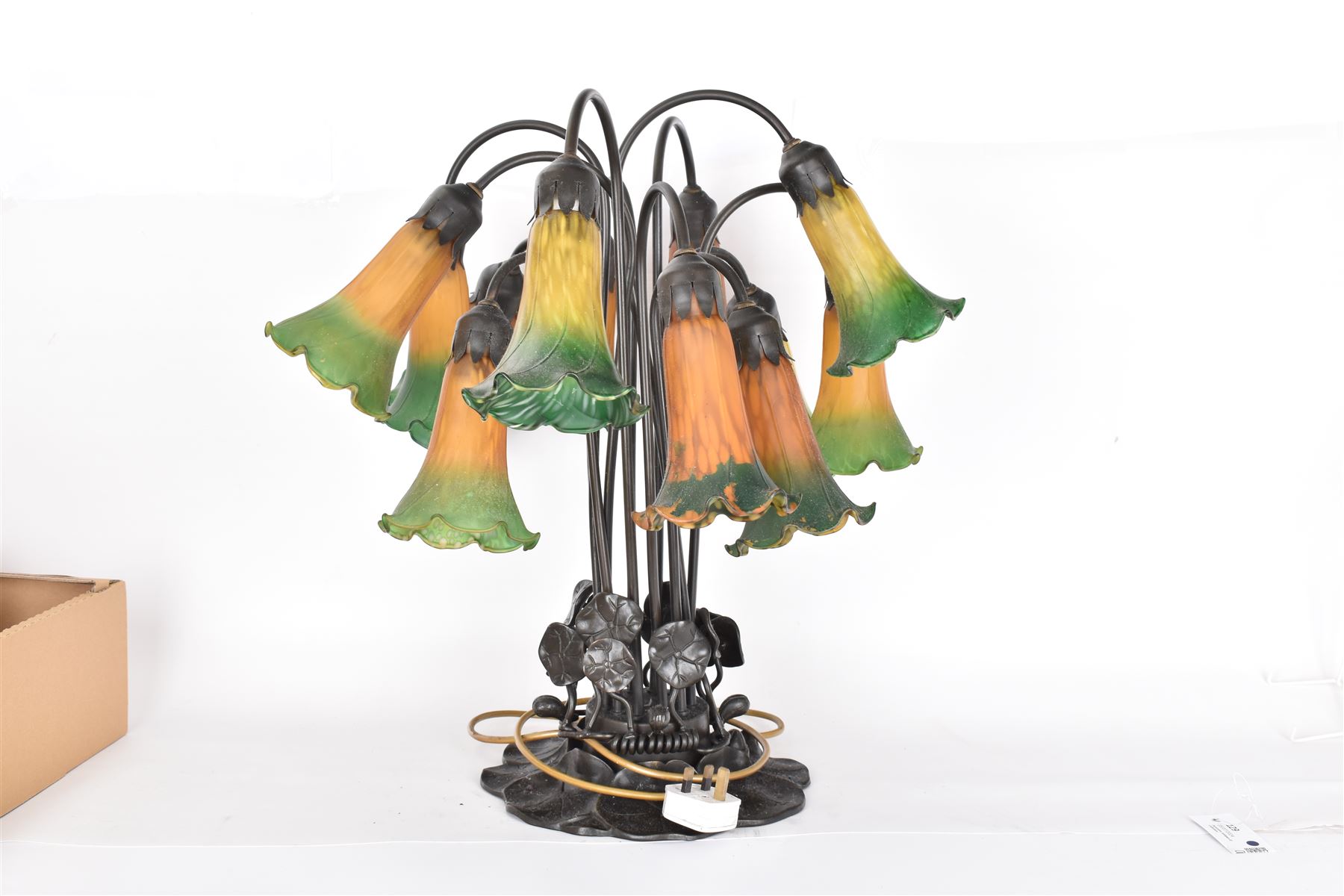 Art Nouveau Tiffany style table lamp, the bronzed base modelled as lily pads leading to tendrils and twelve branches supporting green and yellow glass lily flower shades, H53cm