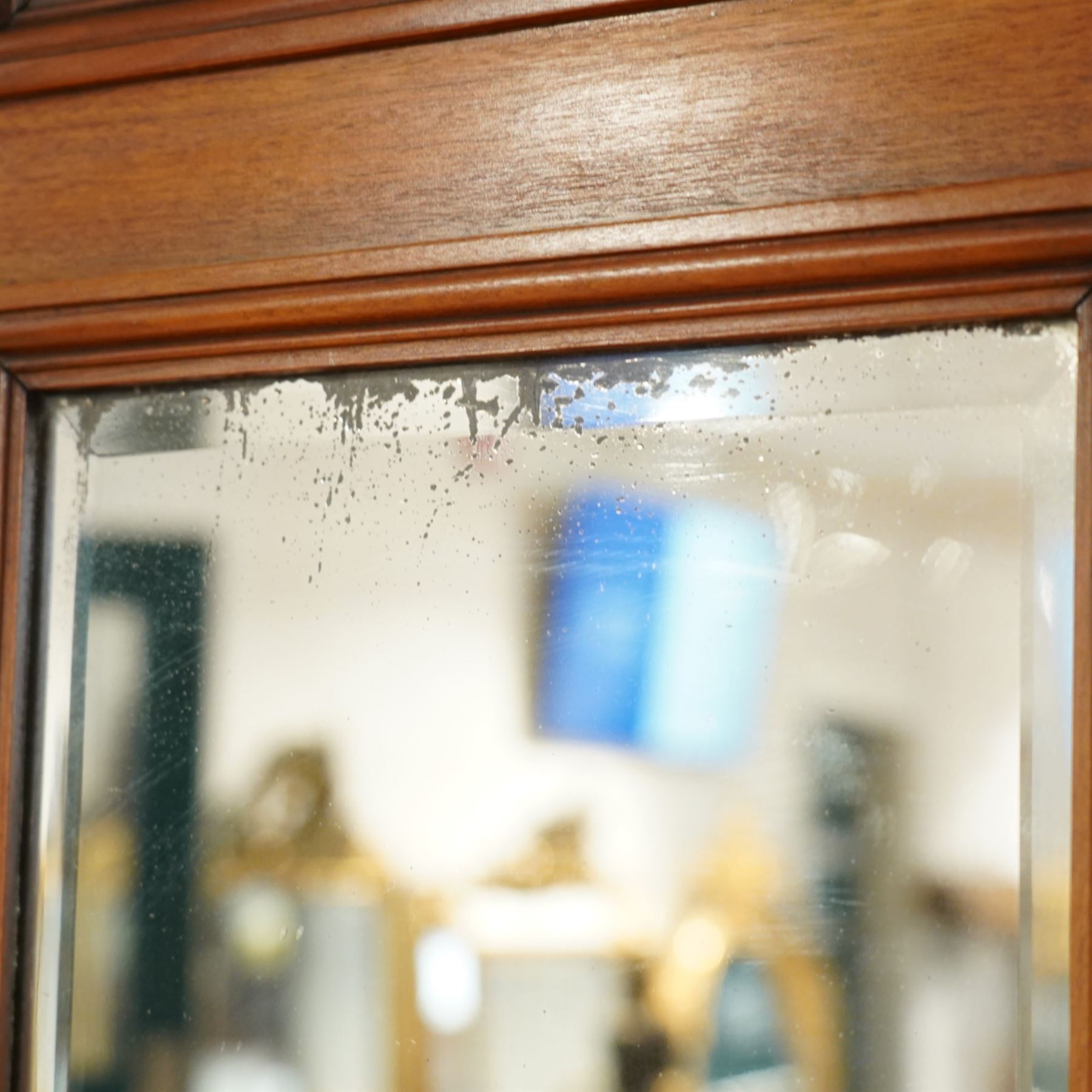 Edwardian walnut triple combination wardrobe, projecting pediment with pierced foliate scroll cresting above a central cupboard flanked by bevelled mirrored doors, the central section with twin panelled cupboard doors carved with foliate scrolls, over open recess with mirrored back and turned supports, above two short and three long drawers with brass handles, interior fitted with hanging rails and shelf, raised on plinth base