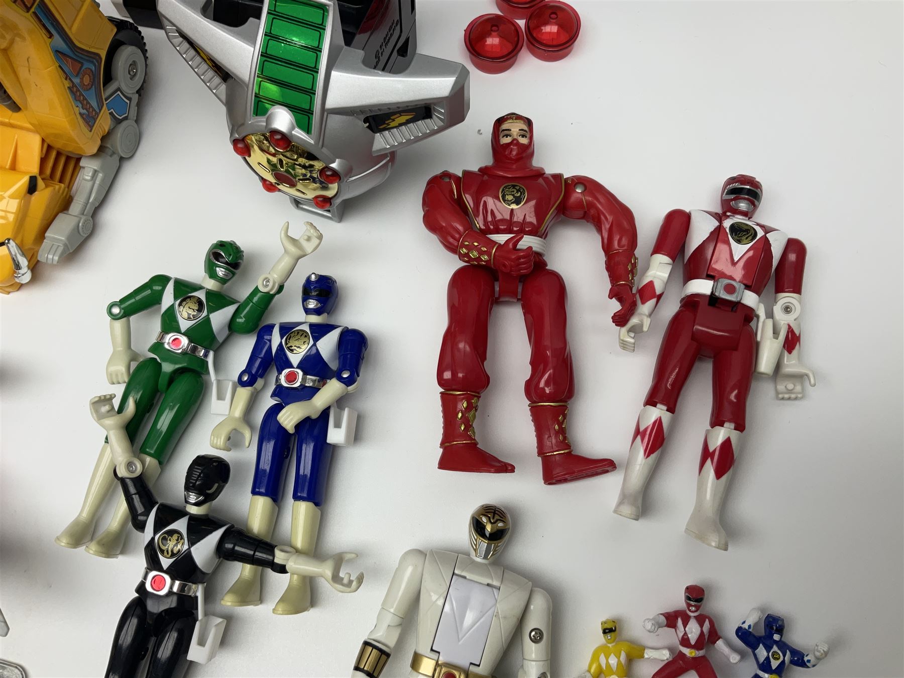 Collection of early 90s Mighty Morphin’ Power Rangers Zords, figures and accessories. Titanus the Carrier Zord, marked Bandai 1991; Green Dragonzord, incomplete; 1994 White Tigerzord with original instruction manual; 1993 Triceratops Dinozord, Mastodon Dinozord and Sabertooth Tiger Dinozord, Pterodactyl Dinozord, missing guns; with 1993 Power Morpher and original Power Coins, with further related figures, accessories and weapons