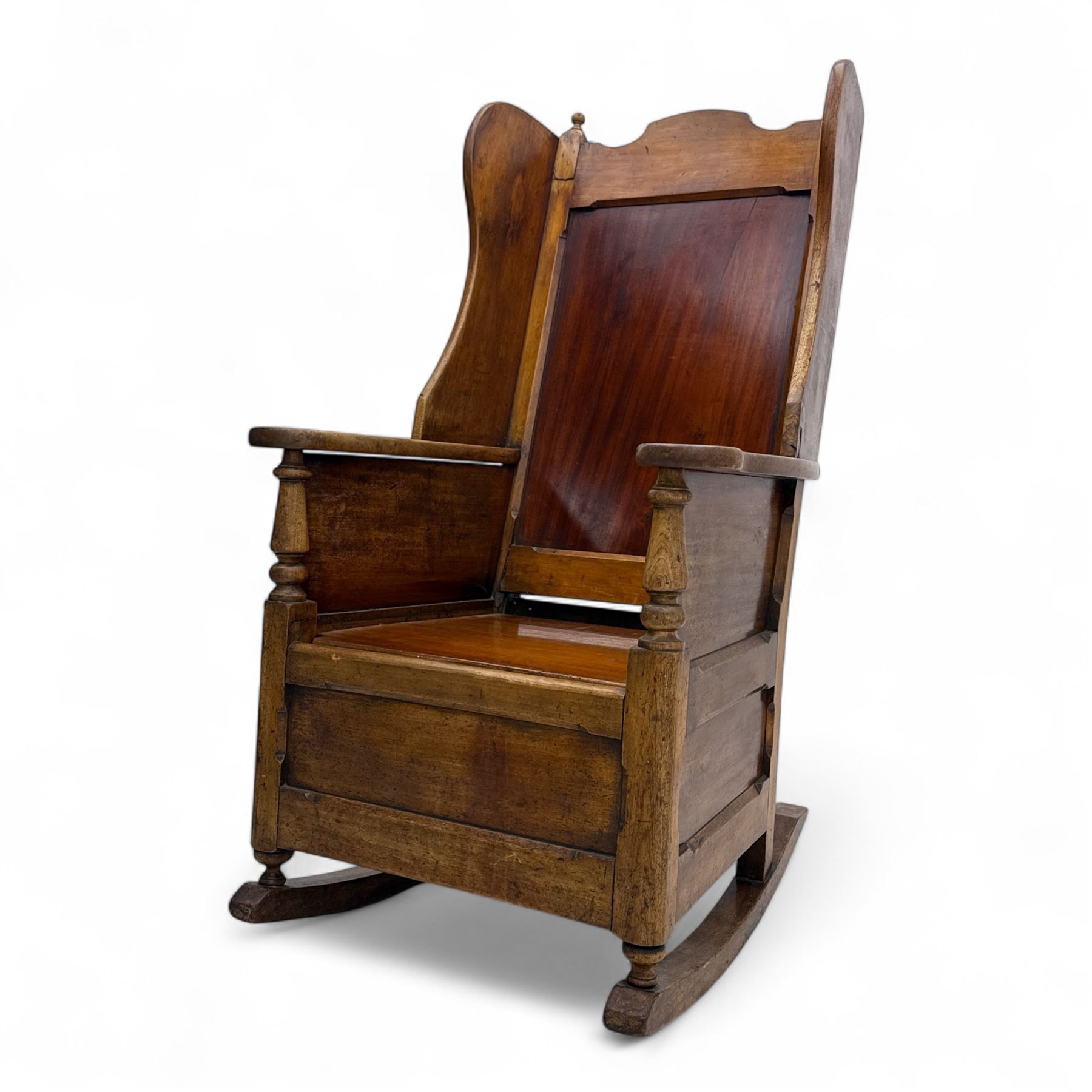 19th-century beech, yew, elm, and mahogany wingback vernacular rocking chair, high back with shaped wings, scroll arms with turned supports, lift-up seat,  square legs on ring turned supports on curved runners 