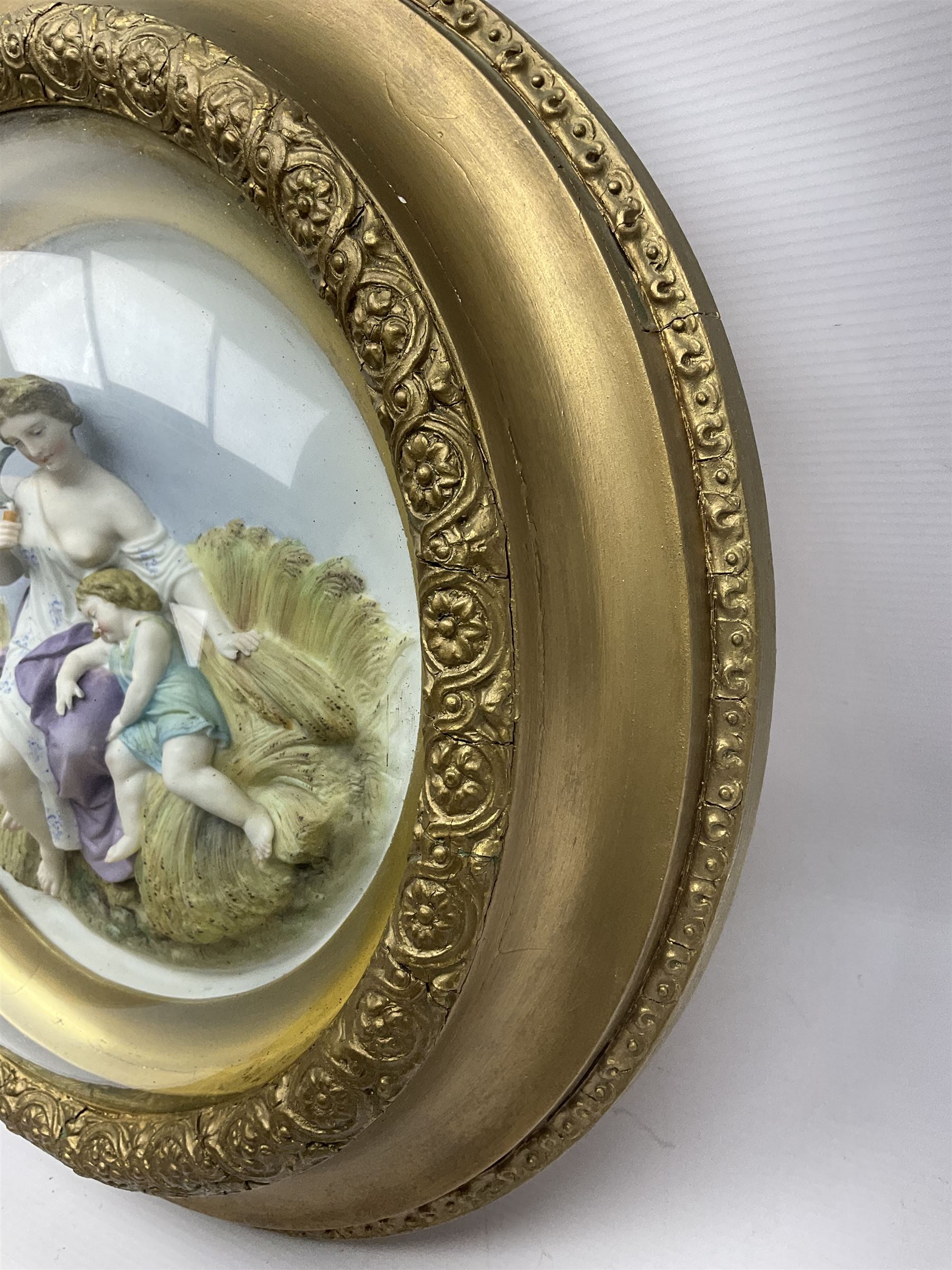 Set of four early 20th century Continental bisque plaques, each of circular form, modelled in high relief as the Four Seasons personified, within gilded circular frames under convex glass, overall D44.5cm