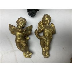 Pair of painted plaster wall brackets, each with a female mask support, her face bronzed with gilt hair and crescent, green acanthus leaves on black ground, L25cm, together with quantity of gilt cherub wall ornaments etc