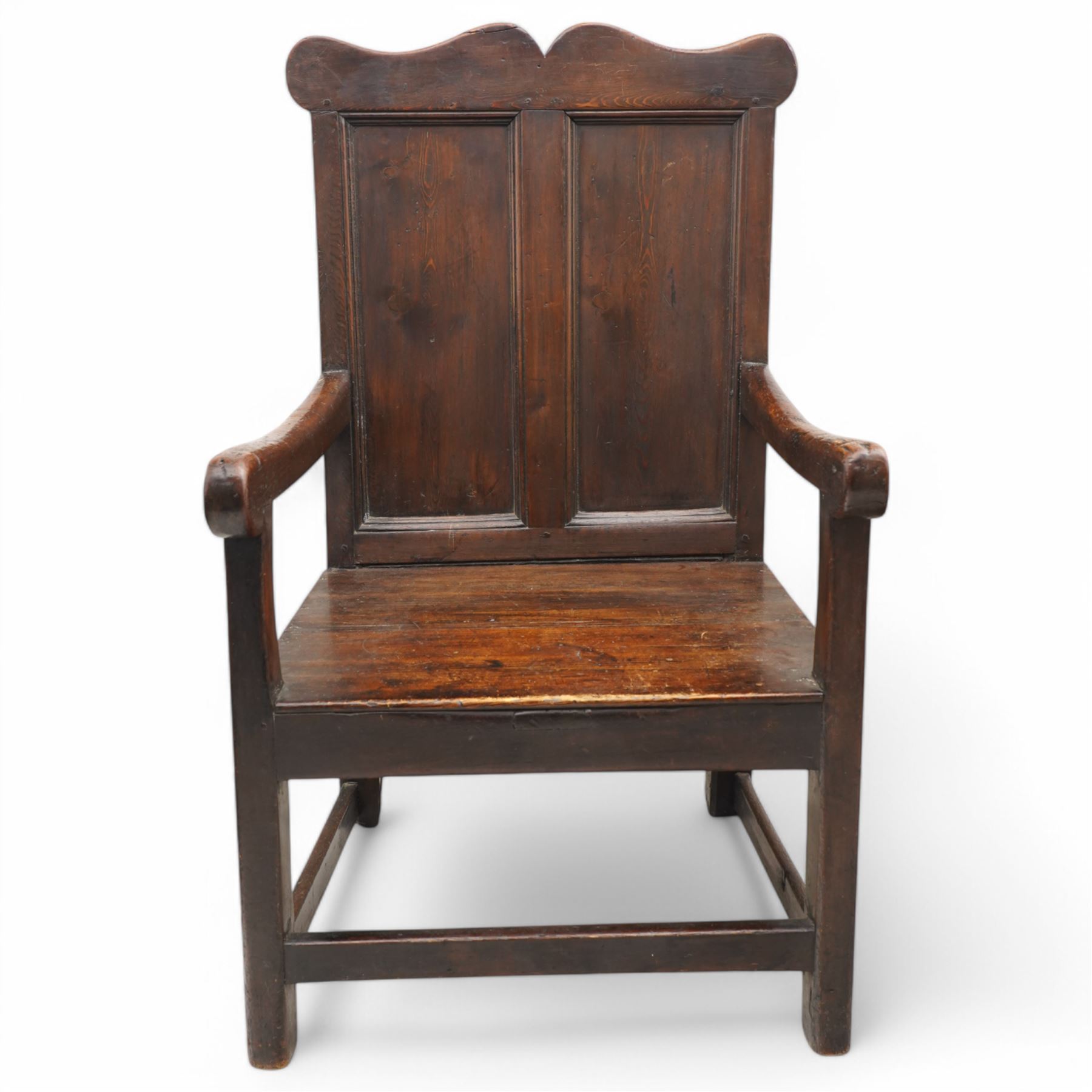 Early 18th century oak open armchair, high back with two recessed panels beneath scrolled cresting rail, curved arms and box seat, raised on square-section supports united by stretchers