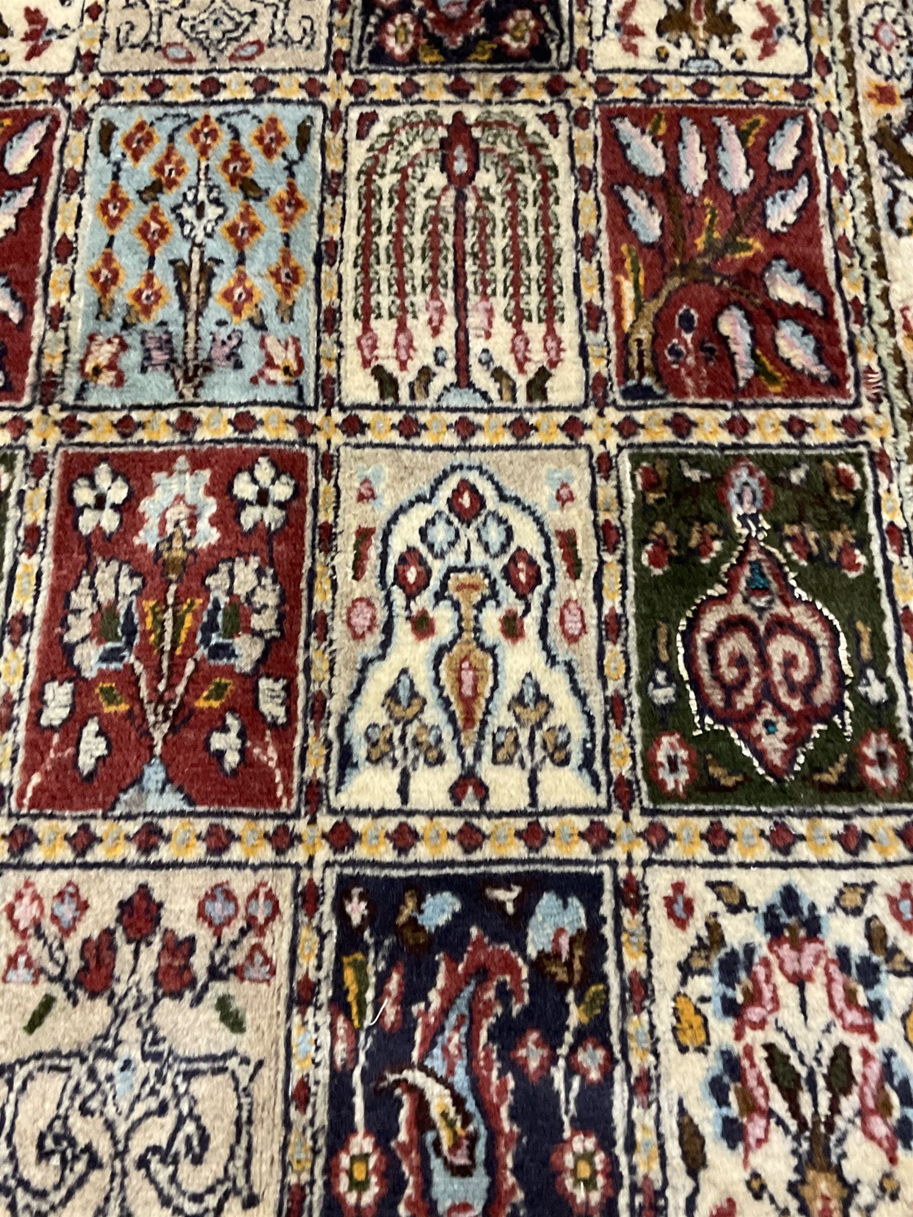 Persian Heriz design rug, ivory ground with rectangular panels each depicting garden scenes of tree of life, plants and Boteh motifs, the guarded border decorated with wildlife and bird scenes