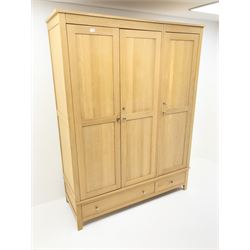 Light oak triple wardrobe, projecting cornice, three doors enclosing fitted interior above one long and one short drawer, stile supports 