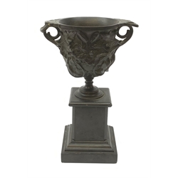 A bronze twin handled urn, cast with acanthus leaves and buds, raised upon a marble plinth with stepped base, (a/f), H25cm