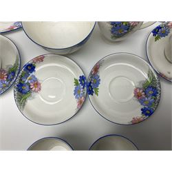 Shelley Strand shaped tea wares, decorated with blue and pink daisies upon a white ground, comprising four teacups, four saucers, three tea plates, milk jug, sugar bowl and cake plate, all with printed green mark beneath and painted pattern no 12216