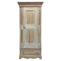 Victorian design lime-washed pine single wardrobe, projecting cornice over panelled door enclosing hanging rail, the lower section fitted with full-width drawer, on shaped plinth base