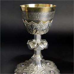20th Century silver plated Gothic chalice, embossed throughout with fleurs de lis, foliate and bead decoration, on a knopped stem with flared and cusped foot, inset with three amethyst and two blue paste stones and applied paste and split pearl brooch, engraved beneath 'In Memory of my Mother R.I.P ... Aug 15th 1937, H23cm