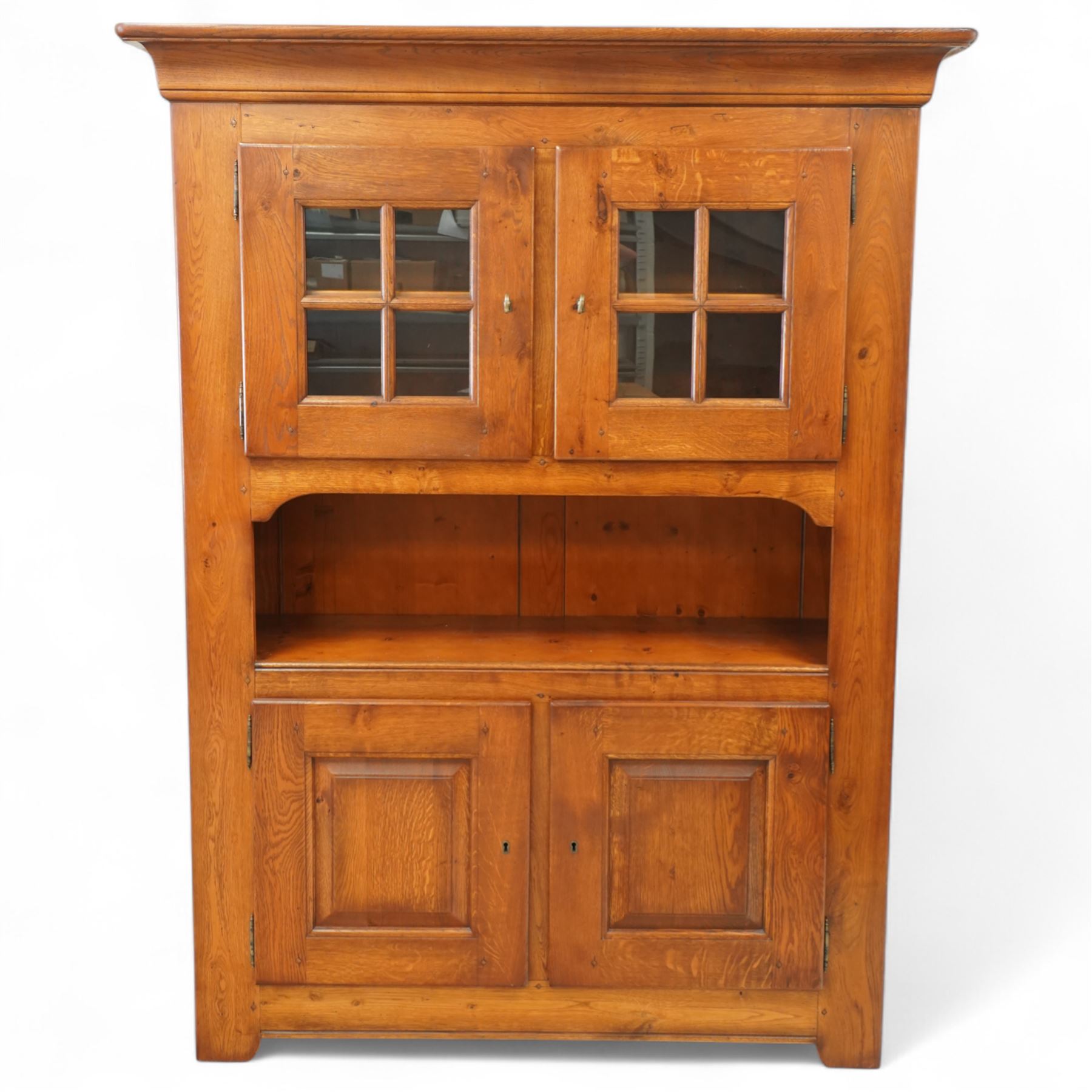 Traditional design solid oak dresser, moulded cornice over twin glazed doors enclosing shelved interior, open centre section, lower base with fielded panel doors opening to shelved cupboards, on plinth base