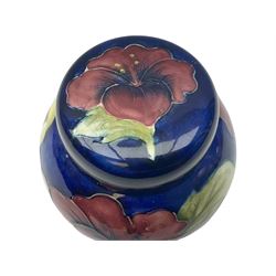 Moorcroft ginger jar, decorated in the Hibiscus pattern upon a blue ground, with paper label beneath detailed 'Potters to the late Queen Mary', H11cm.