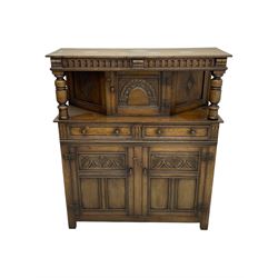 Jacobean design oak court cupboard, upper section with carved arched panelled cupboard door flanked by turned columns, beneath carved and moulded frieze, lower section fitted with two drawers over two cupboard doors with gothic arched panel decoration, raised on stile supports