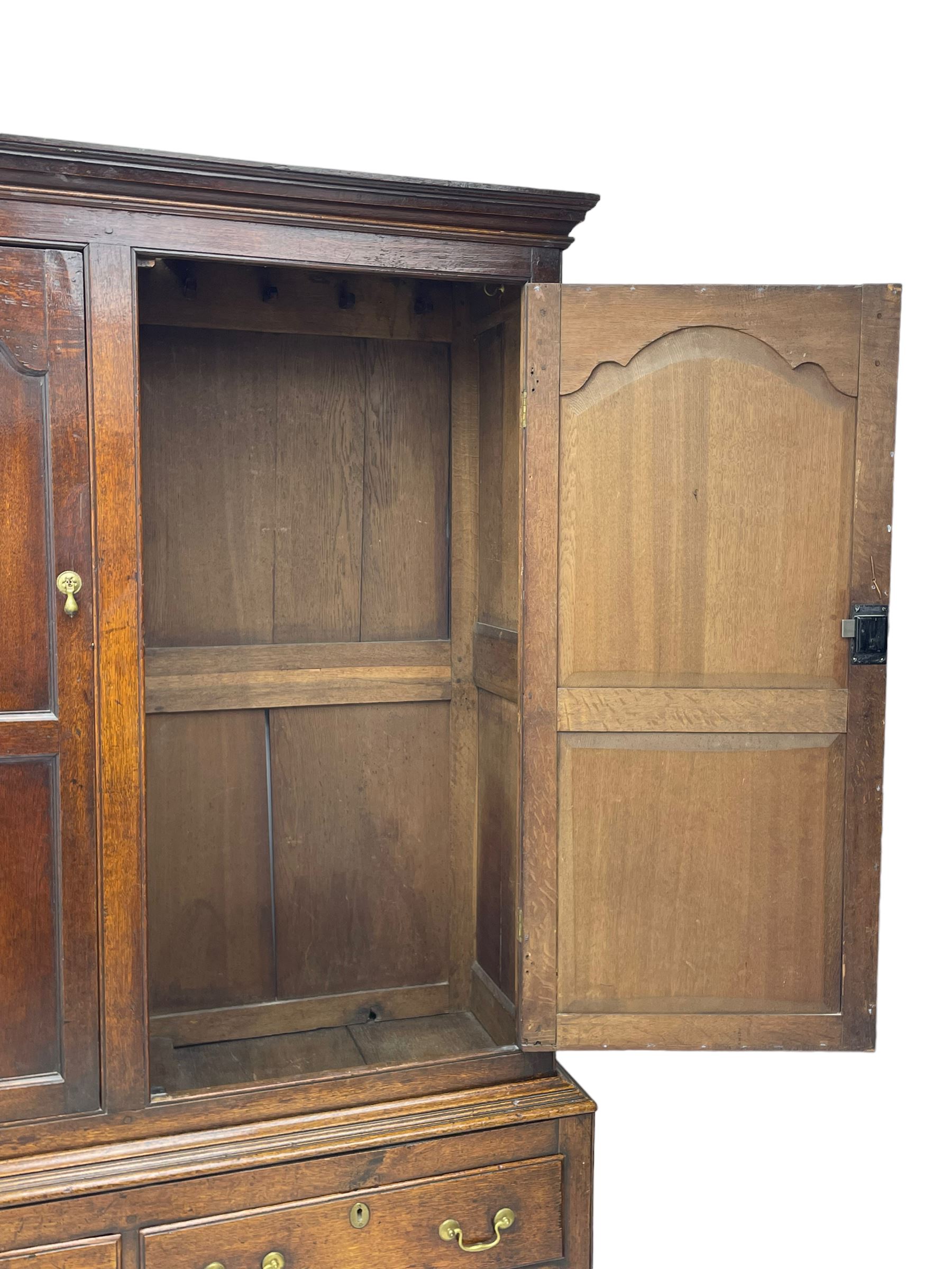 George III oak livery cupboard, projecting moulded cornice over two panelled doors, the upper panels within stepped ogee and arched moulded frame, the interior fitted with a single row of wooden hooks, two short and one long drawers, on bracket and return skirted base 