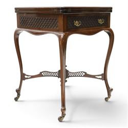 Edwardian carved mahogany envelope card table, the rectangular quadruple hinged top enclosing baize-lined interior, the single frieze drawer and sides with blind-fretwork carving, over cabriole supports with scroll feet and castors united by pierced lattice fretwork X-stretcher with turned finial