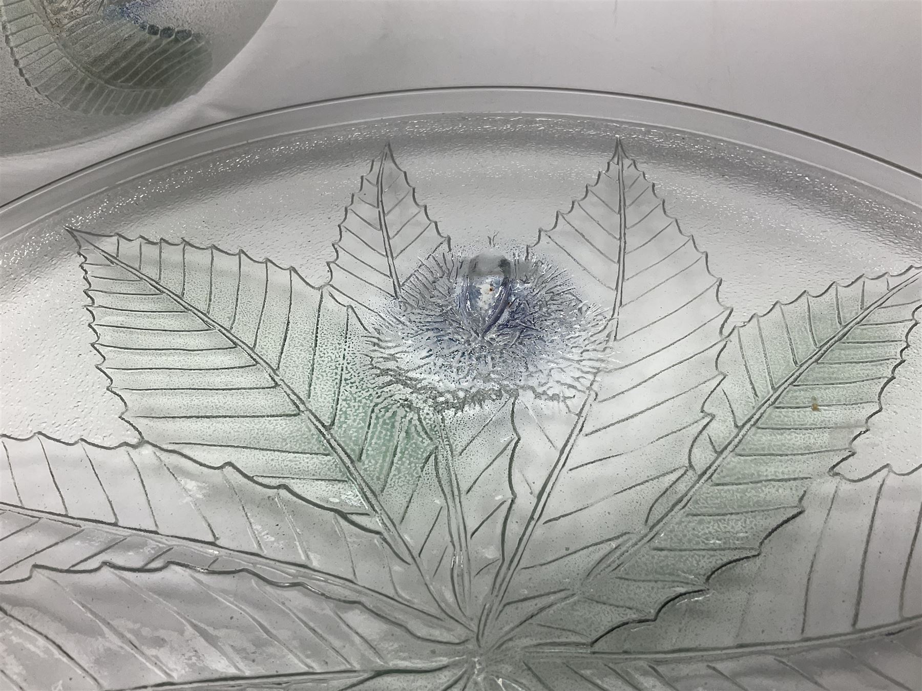 Two French pressed glass bowls of shallow circular form, relief moulded with flowers and foliage, together with a matching charger, largest bowl D34cm  