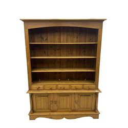 Early 20th century pine kitchen dresser, featuring a hutch with arched top over three open shelves, the base with five drawers over three cupboard doors, turned column supports flanking the doors, scalloped apron base with bracket feet