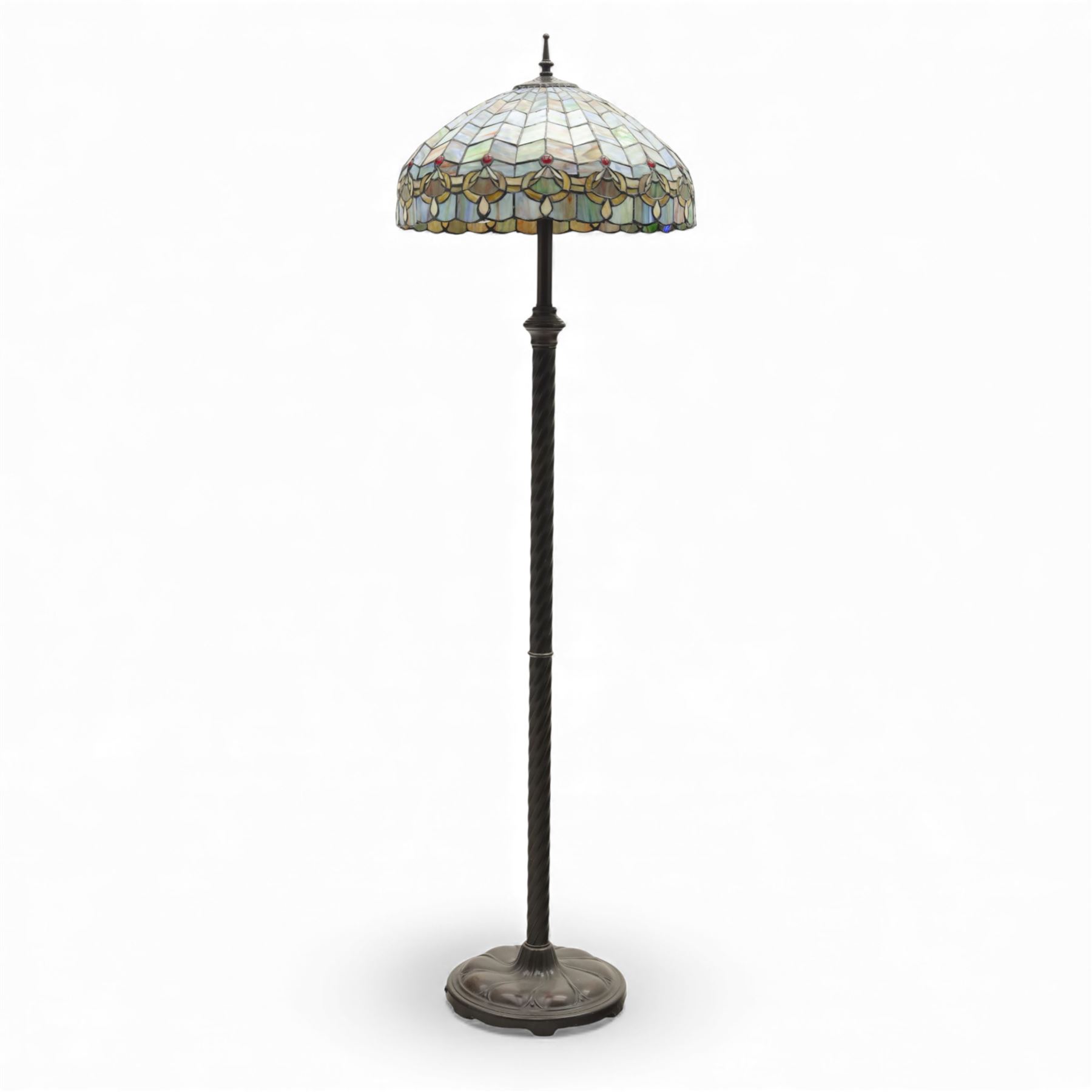 Late 20th century Tiffany style standard lamp, the leaded glass domed shade composed of geometric panels in mottled pastel tones, bordered by stylised foliate motifs and coloured cabochons, raised on a spiral twist metal column and circular moulded base