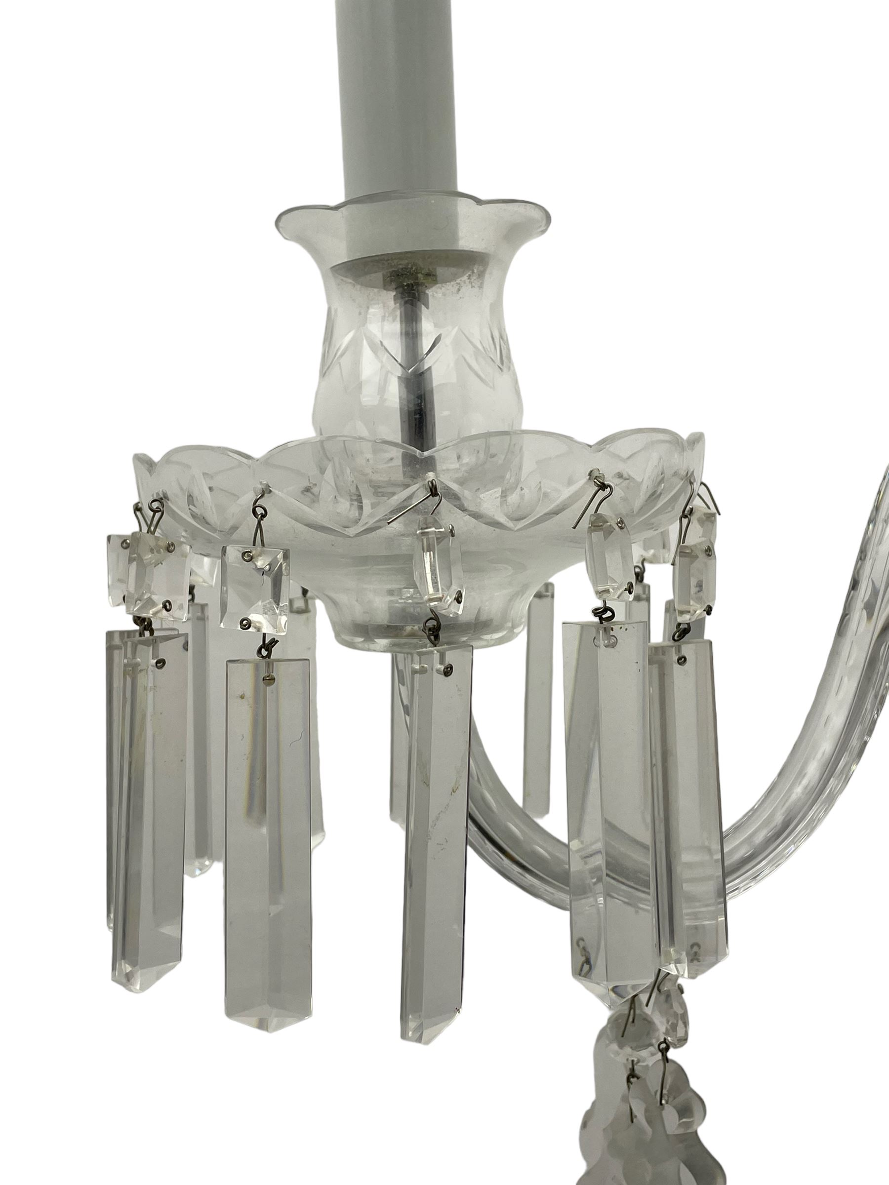 Pair of cut glass two branch wall sconce candelabras, each with S scroll extending branches with shaped and bevelled circular drip trays, hung with pendant drops