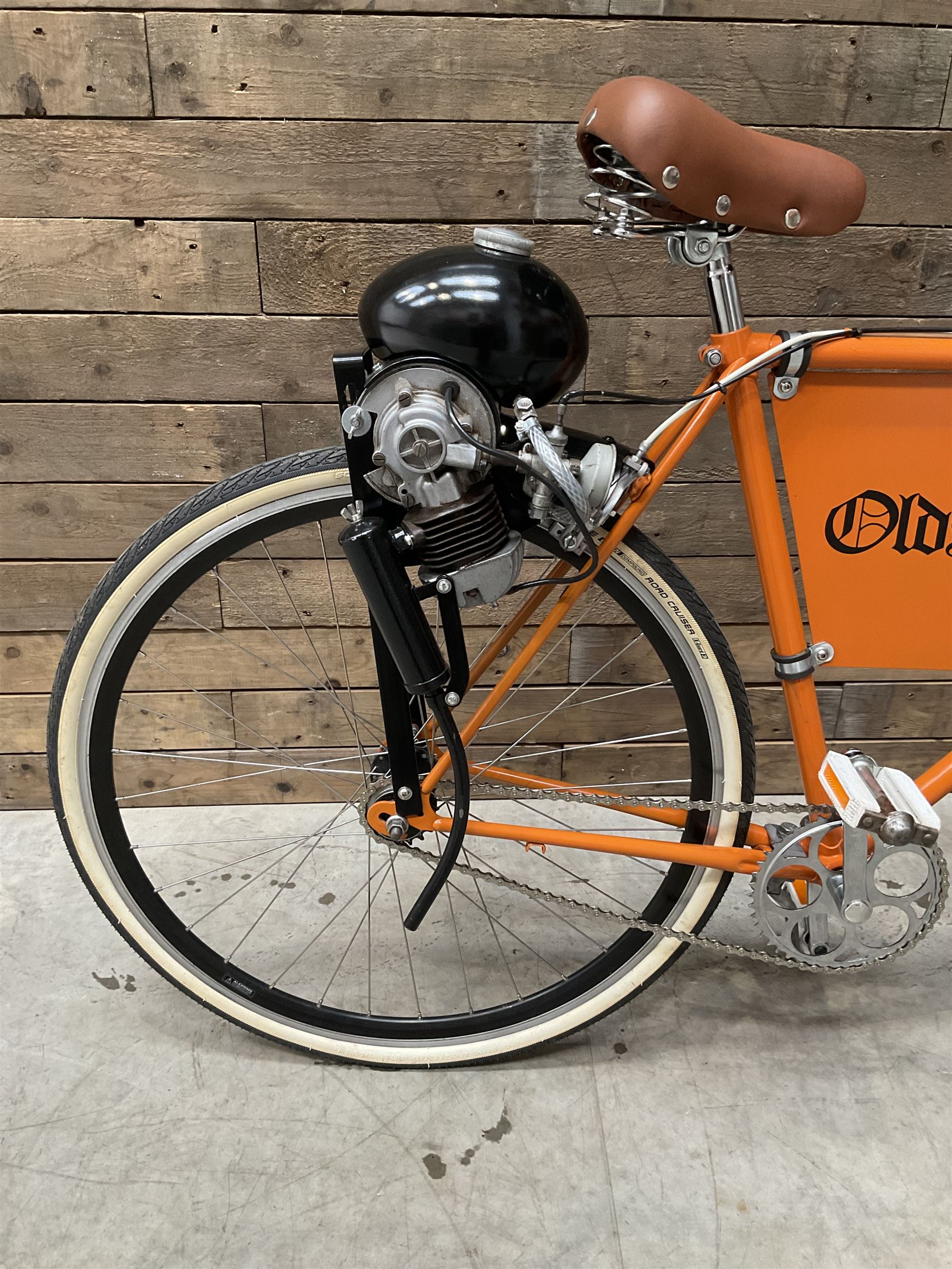 Fully restored vintage advertising bicycle with 2 stroke petrol engine, orange frame, tan leather seat