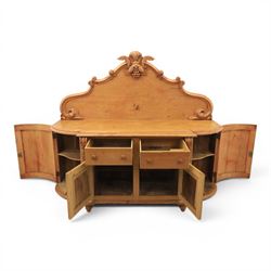 Victorian pine chiffonier, shaped moulded top with raised scroll carved back surmounted by carved fruit and foliate crest, fitted with two frieze drawers over two panelled cupboard doors, the outer cupboards of bowed form, carved foliate corbels, on plinth base