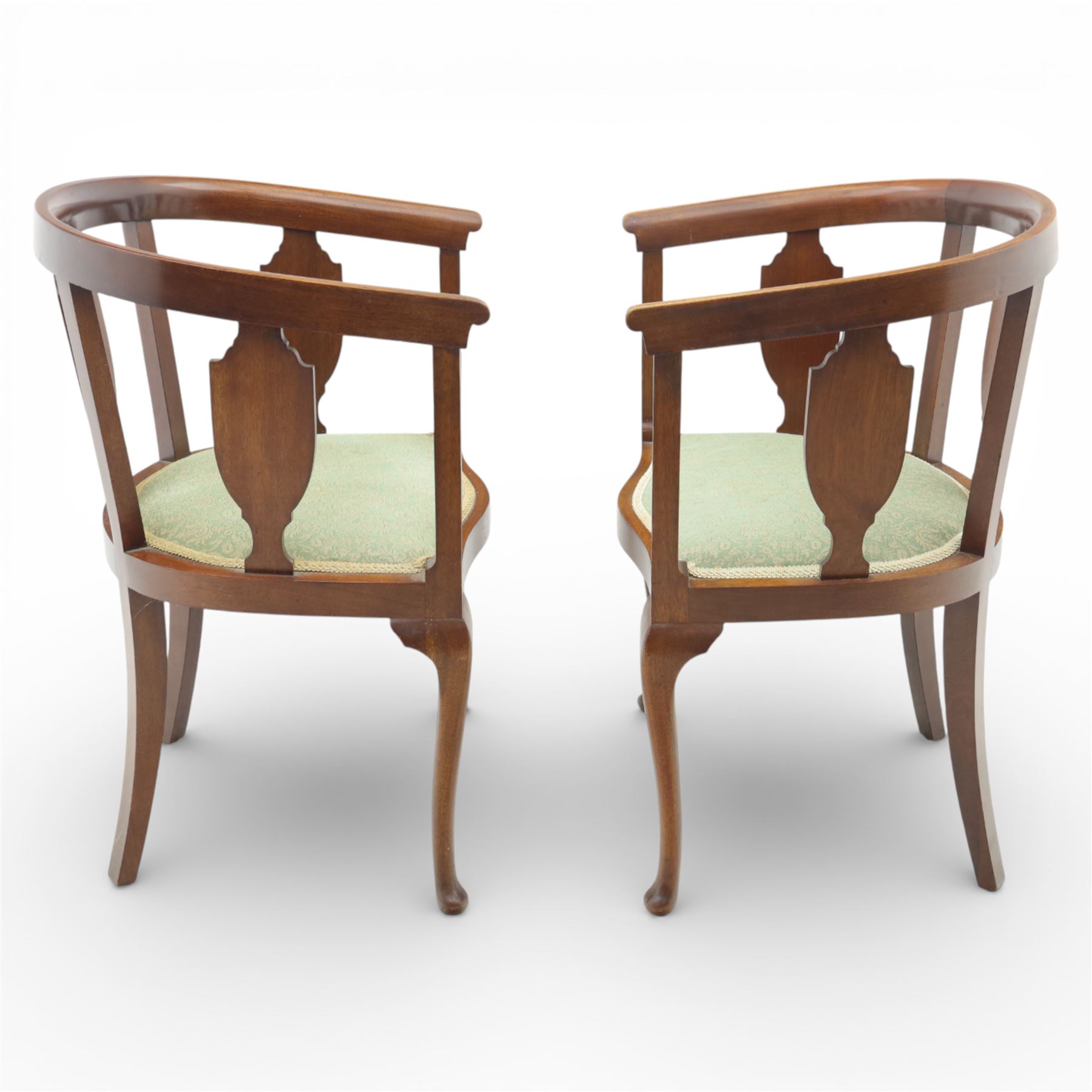 20th century mahogany tub chairs, the arched backs enclosing shaped splat panels and plain uprights, open curved arms flowing into the seat rails, upholstered seats in green foliate patterned fabric, on cabriole legs