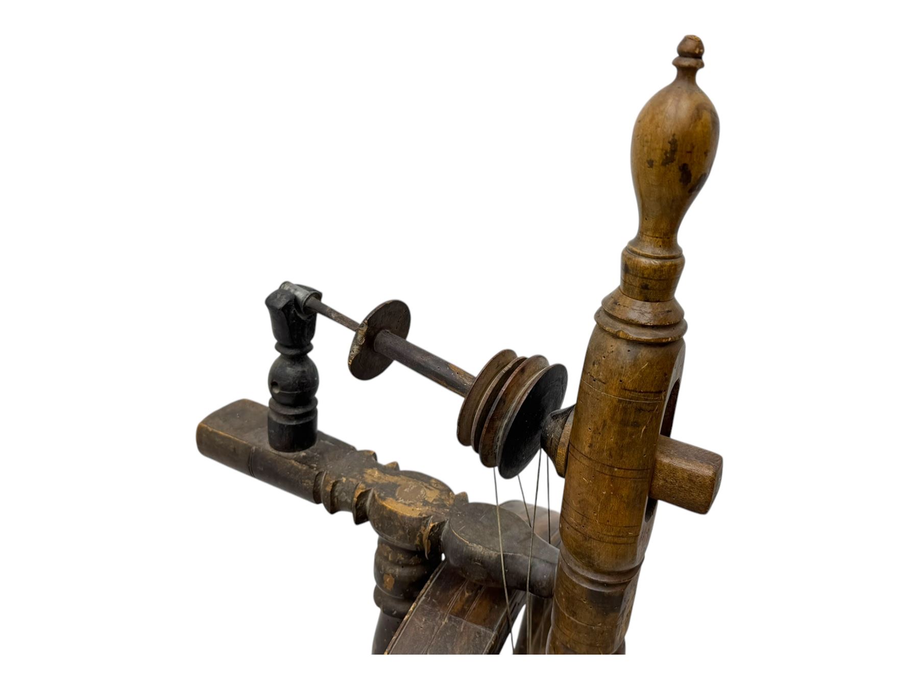Late 19th century turned beech spinning wheel, upright form with single treadle, triangular base, and a flyer and bobbin assembly surmounted by a turned finial.
