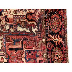Persian Heriz red ground carpet, large stylised pole medallion surrounded by Pitrak motifs, indigo ground border decorated with stylised flower heads and trailing leafy branches, within floral pattern guard stripes
