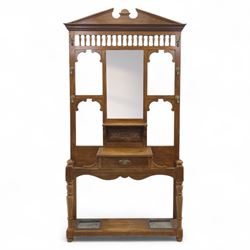 Edwardian walnut hall stand, the shaped pediment above turned spindle gallery and bevelled mirror, fitted with brass double coat hooks, single drawer with cast handle and carved frieze, flanked by turned supports, lower platform fitted with twin metal drip trays