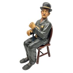 Large painted composite figure of Charlie Chaplin, seated upon wooden chair, H54cm