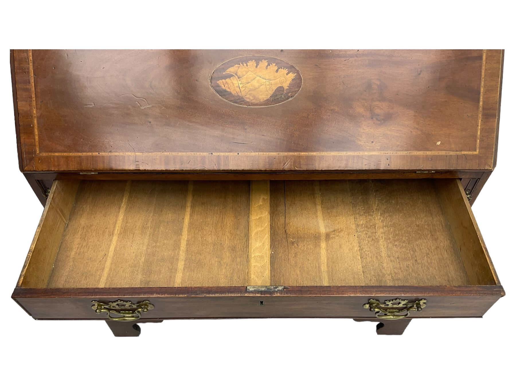 George III mahogany bureau, the conch inlaid fall front enclosing pigeon holes, shelves and central cupboard with inlaid flower motif, four graduating cock-beaded drawers below each with brass handles, lower moulded edge over shaped bracket feet