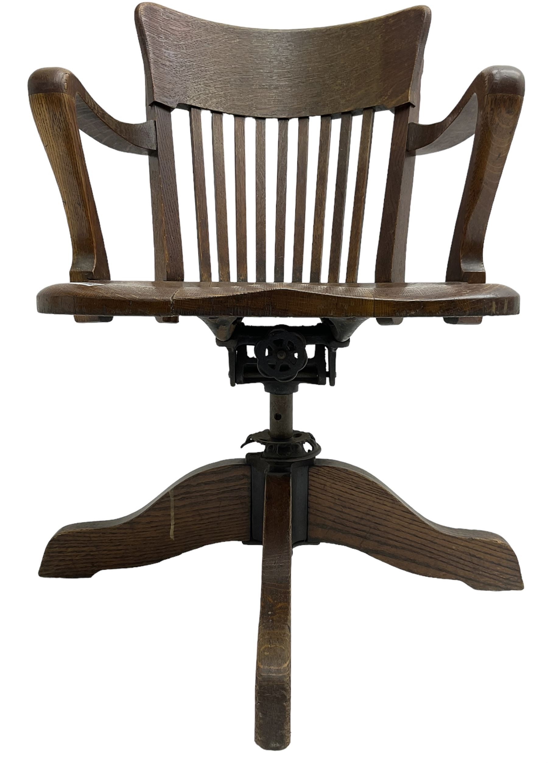 Early 20th century swivel office desk chair, shaped bar back over vertical rails, dished seat, on four splayed supports