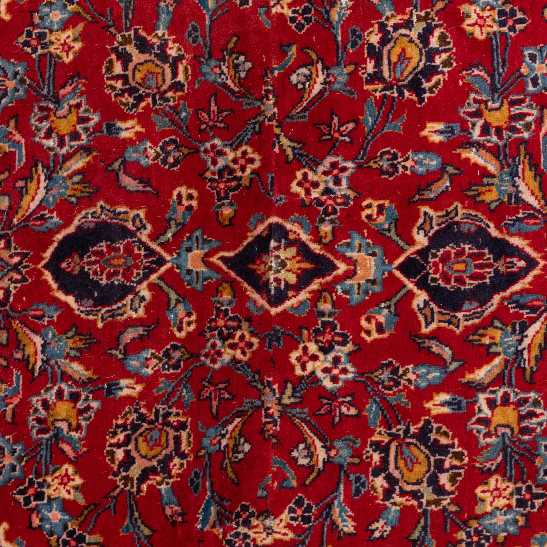 Two Persian rugs, the larger with a crimson field decorated with three linked indigo medallions amongst flowering tendrils, shaped floral spandrels and an indigo palmette border, (161cm x 129cm), the smaller with a crimson field centred by an ivory rosette amongst stylised flowering plants, within a dark floral border, (114cm x 79cm) (2)