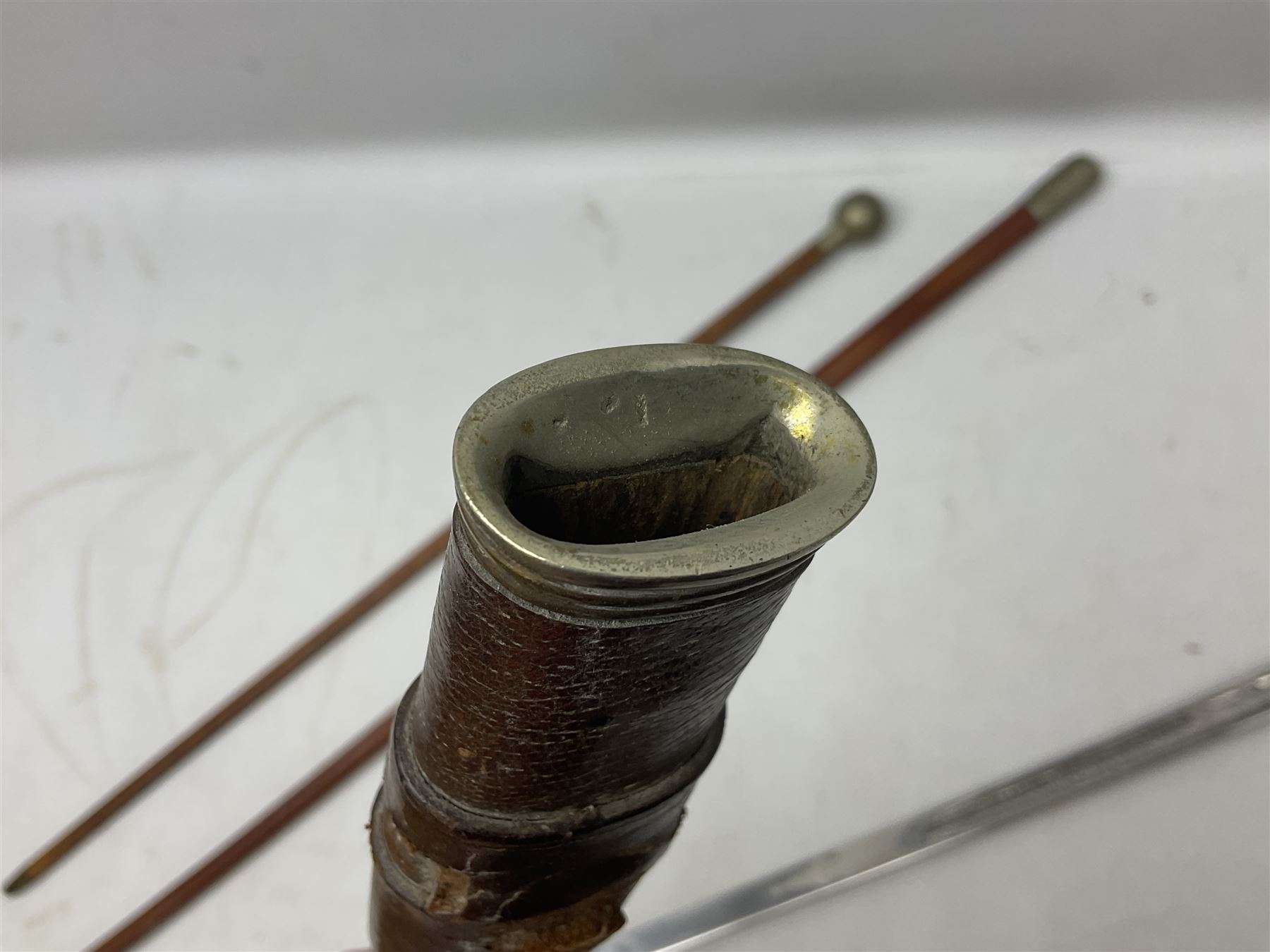 George V 1897 pattern Army Officer's sword by Henry Wilkinson Pall Mall London, the 82.5cm 'London Made' blade etched to both sides with Royal Crests and cyphers etc, pierced half-basket hilt with wire-bound fish skin grip and remains of leather knot strap; in leather covered field service scabbard L101cm overall; and two 14th Prince of Wales Own swagger sticks (3)