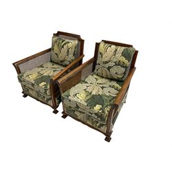 Early 20th century bergère lounge suite, mahogany framed with cane work back and sides, acanthus scroll carved uprights - three seat sofa (W167cm, H82cm, D83cm), and pair matching armchairs (W78cm), loose cushions upholstered in acanthus leaf scroll fabric with scatter cushions