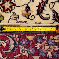 West Persian Sarough hand-knotted rug, ivory field decorated with finely drawn symmetrical lattice of scrolling vines, palmettes and flowering sprays issuing from a subtle central medallion, enclosed by a broad madder-red border of stylized palmettes and foliate vine ornament between multiple guard stripes, with cotton fringe ends 