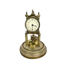 German - Gustav Becker BHA torsion clock c1900 on a circular stepped brass base with a glass dome, skeleton movement raised on two pillars with finials, small enamel dial with arabic numerals, spade hands and a adjustable rotary pendulum, torsion spring intact.