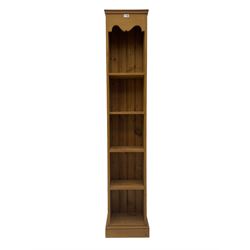 Pine narrow open bookcase, shaped frieze over four shelves, on plinth base