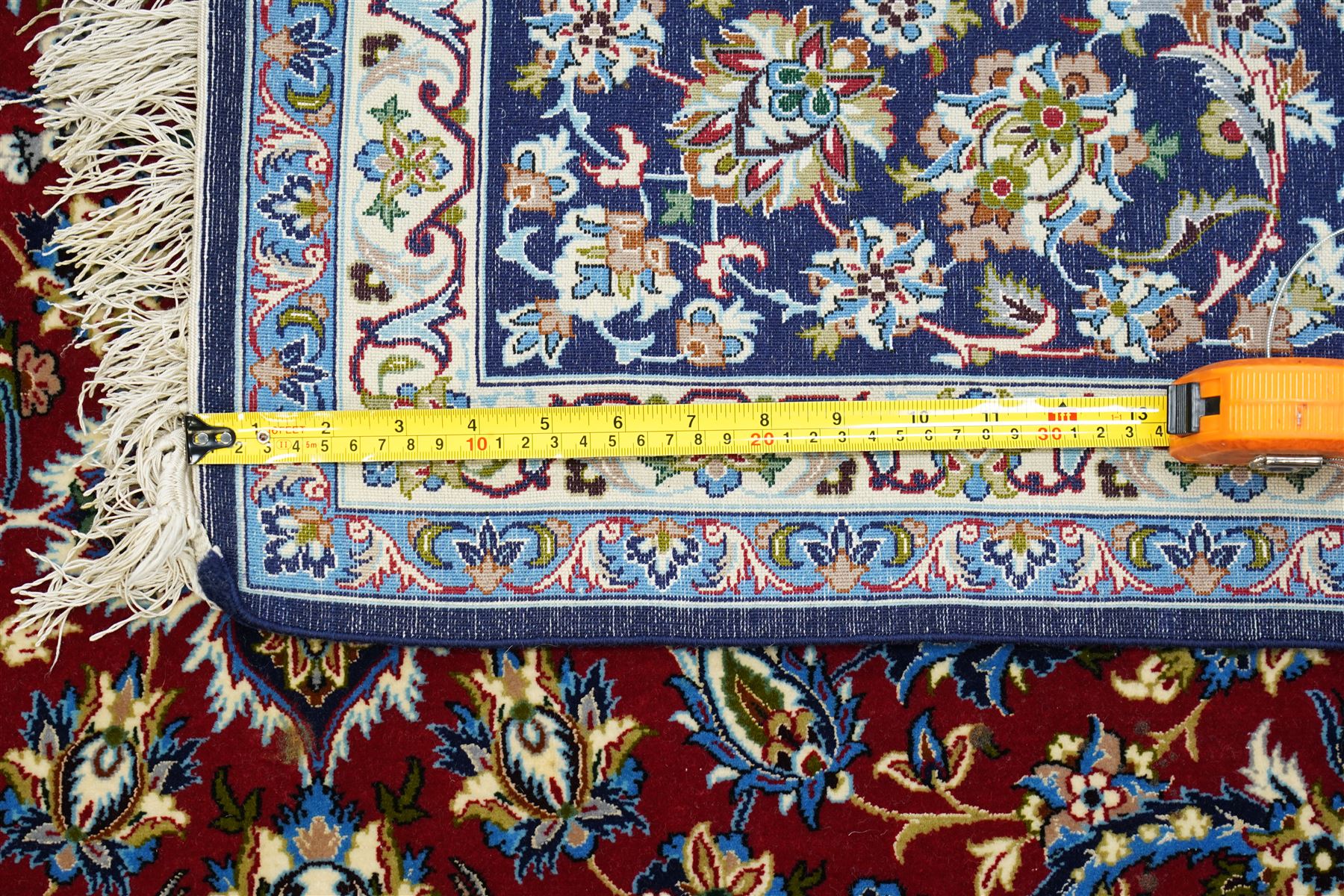 Fine Central Persian Isfahan hand-knotted rug, madder red field with central finely drawn foliate medallion issuing an intricate all-over scrolling vine design with palmettes and arabesques, enclosed by multiple conforming borders in navy ground, signed Isfahan in cartouche, silk fringe ends 