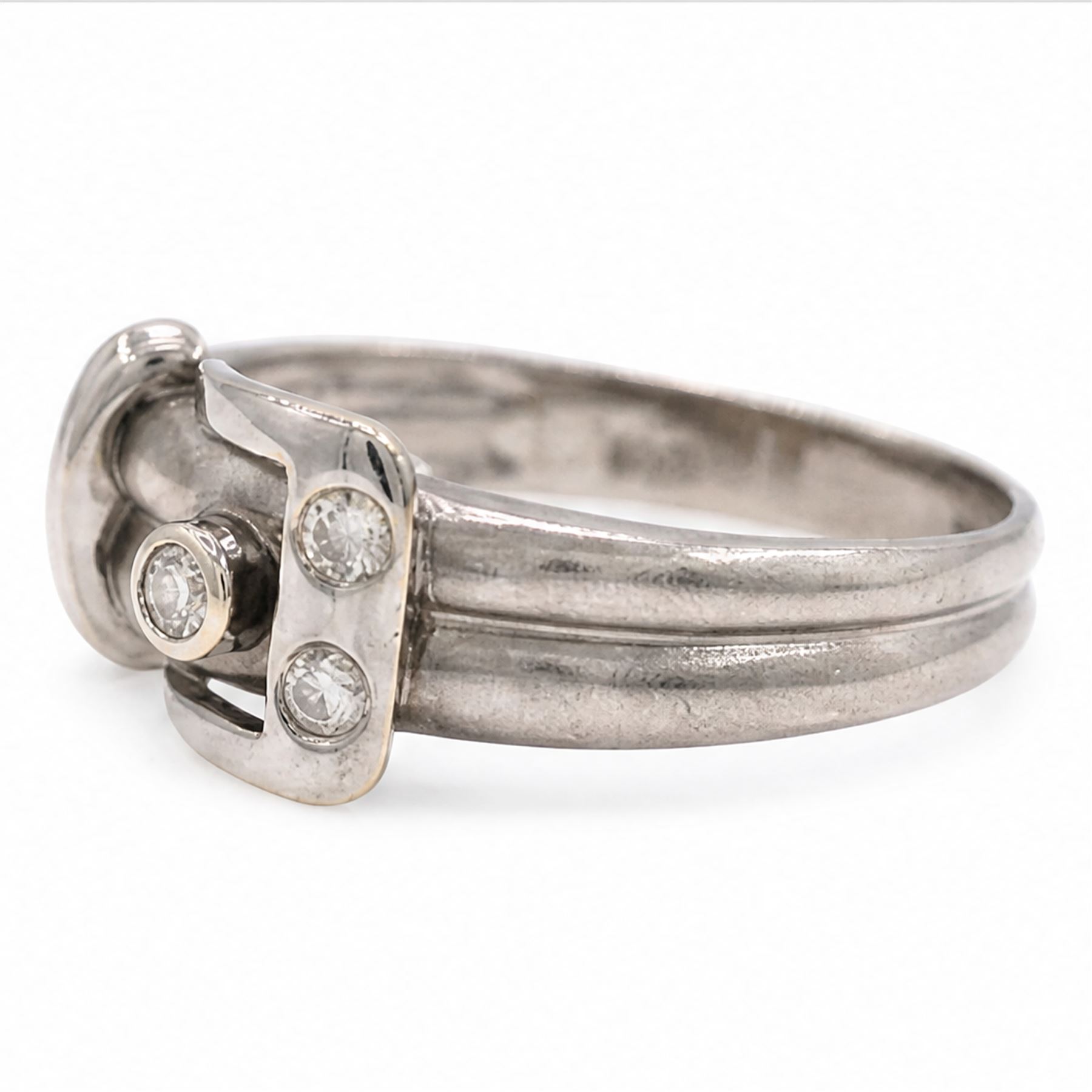 14ct white gold three stone diamond buckle ring, bezel and rubover set with three round brilliant cut diamonds, to a brushed and polished gold band, stamped 585