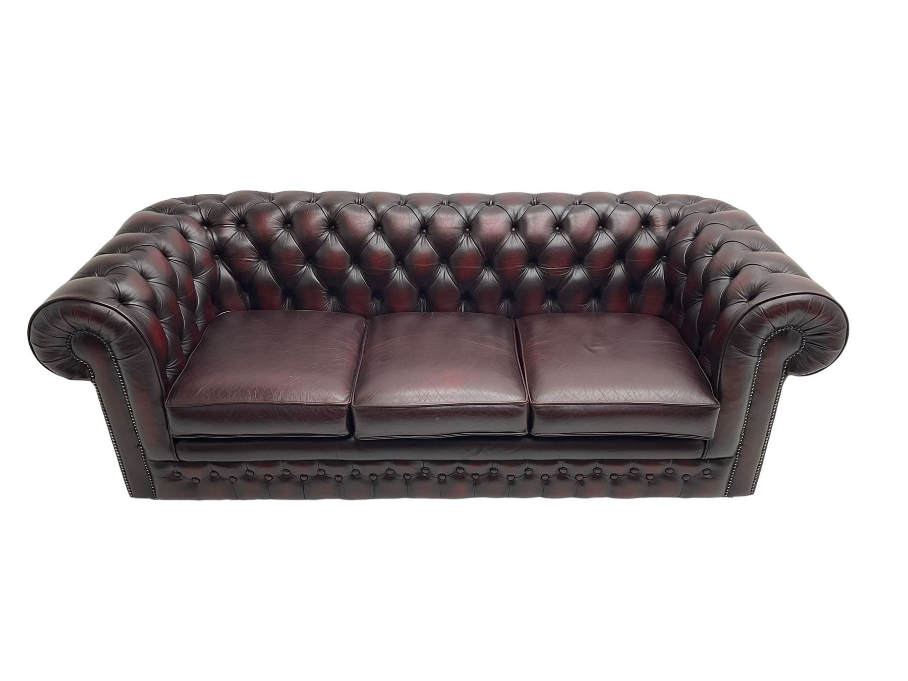 Thomas Lloyd - three seat Chesterfield sofa, upholstered in buttoned oxblood leather, on castors 