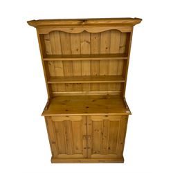 Pine dresser, raised rack fitted with two shelves, the base enclosed by two panelled doors and fitted with internal drawers, plinth base