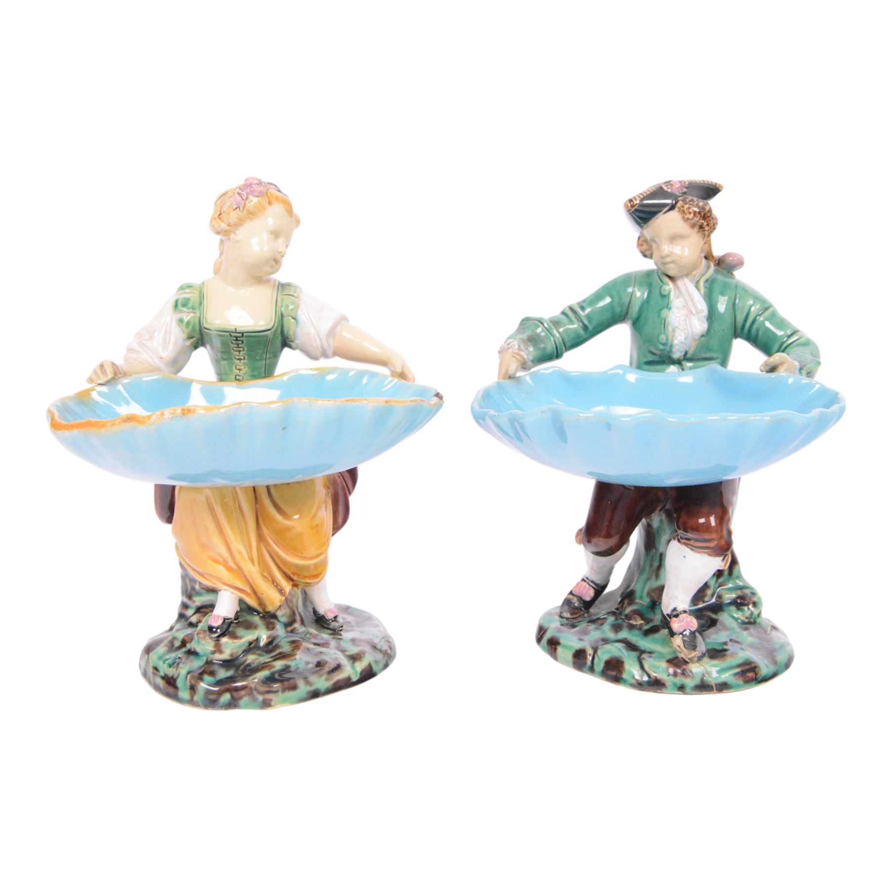 Pair of Minton majolica Hogarth figures, modelled as a seated boy and girl, on tree stumps, both holding sweetmeat dishes, with impressed marks beneath, H18cm 