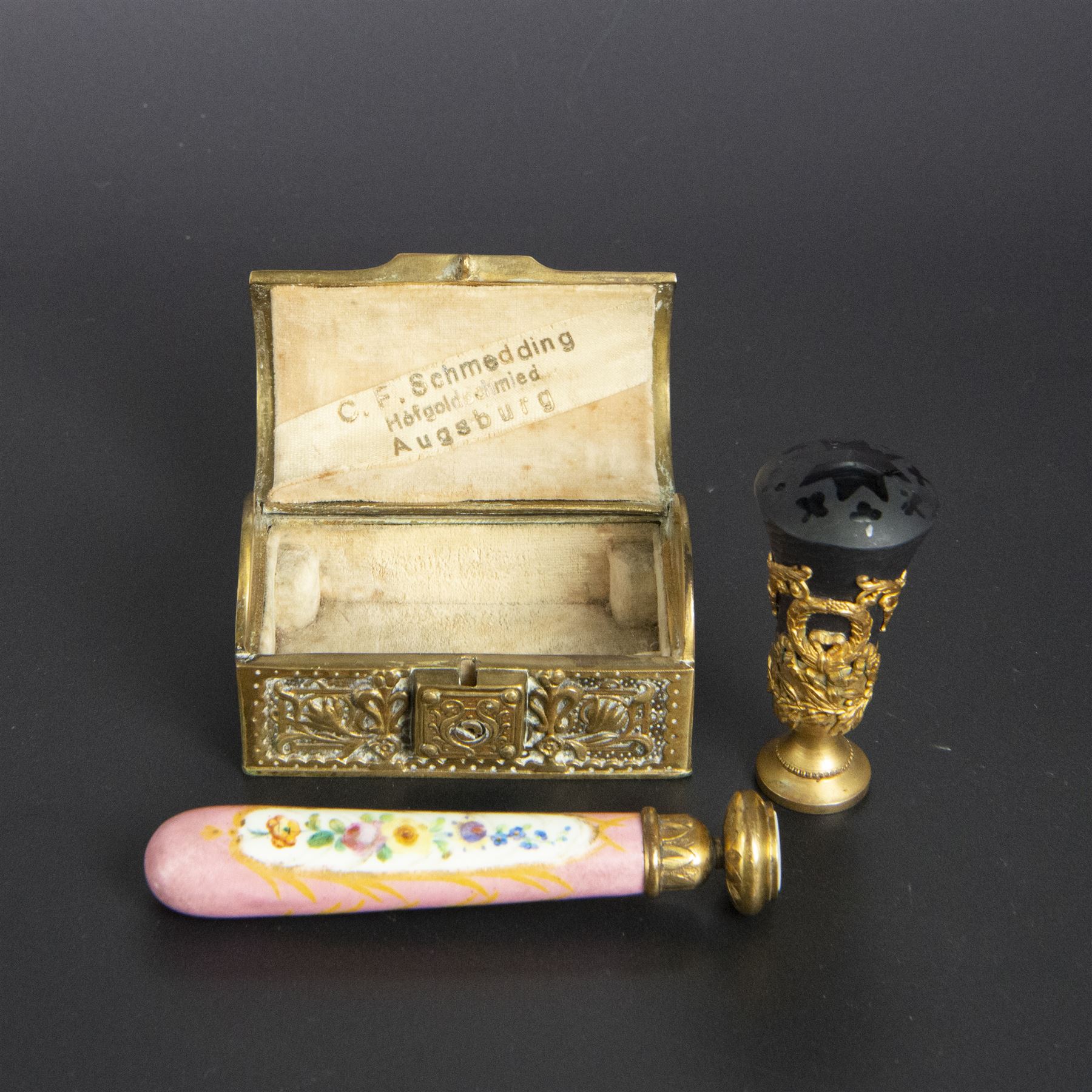 Gilt bronze mounted black glass seal, contained within a brass casket, with velvet interior and inner label reading 'C. F. Schmedding Augsburg', together with a porcelain handled seal decorated with floral sprays on a pink ground