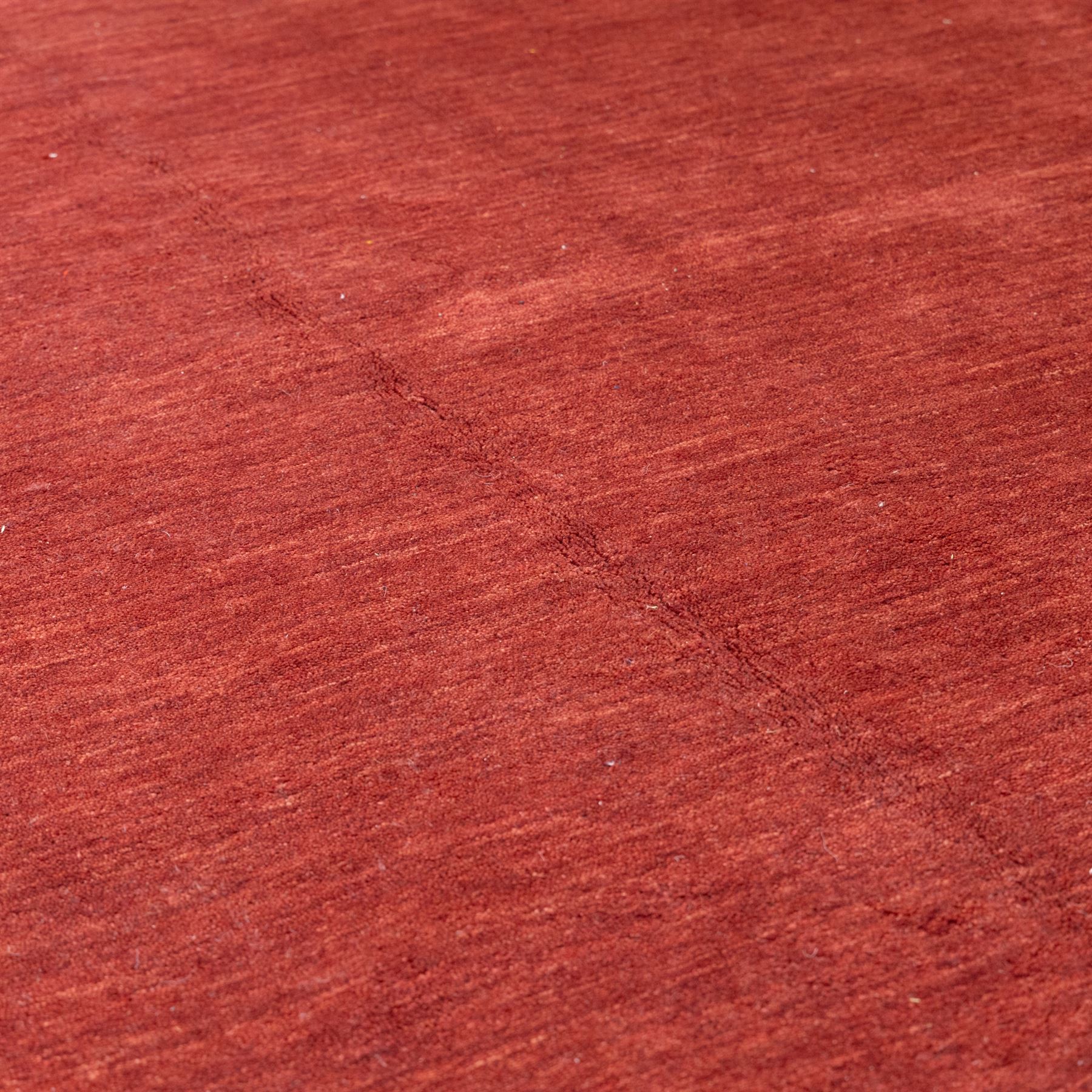 Modern Gabbeh red wool rug, plain madder red field with subtle tonal variation and abrash