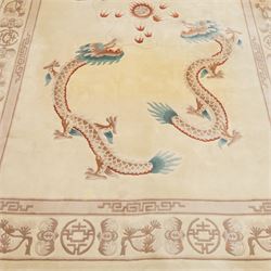 Late 20th century Chinese wool carpet, cream field with five stylized dragons arranged in a circular formation around a central flaming pearl motif, dragons depicted with elongated bodies and clawed feet amongst stylized cloud forms, enclosed within a narrow inner border and a wider outer border decorated with traditional Chinese motifs and symbols