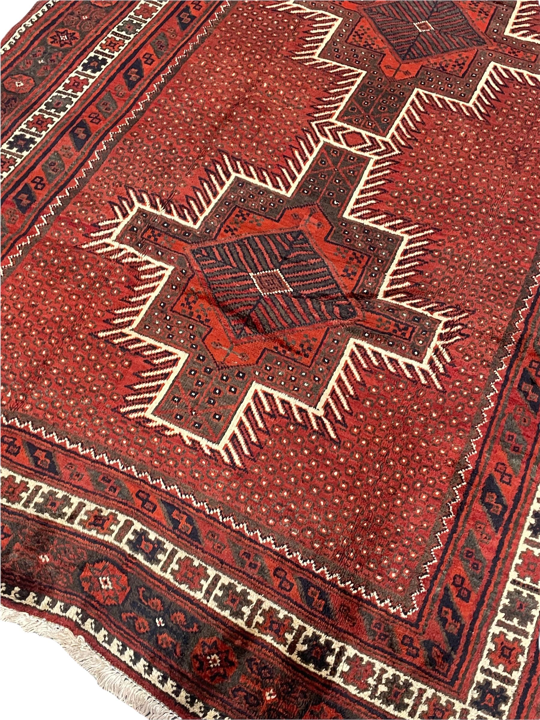 Persian Kelardasht red ground rug, the field decorated with two geometric medallions, multi-band border decorated with stylised flower heads and geometric repeating patterns