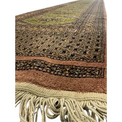 Pakistani olive and rose ground runner rug, the field decorated with repeating hexagonal medallions, surrounded by a rose-hued field with repeating diamond patterns, the borders featuring geometric motifs and trailing foliate designs