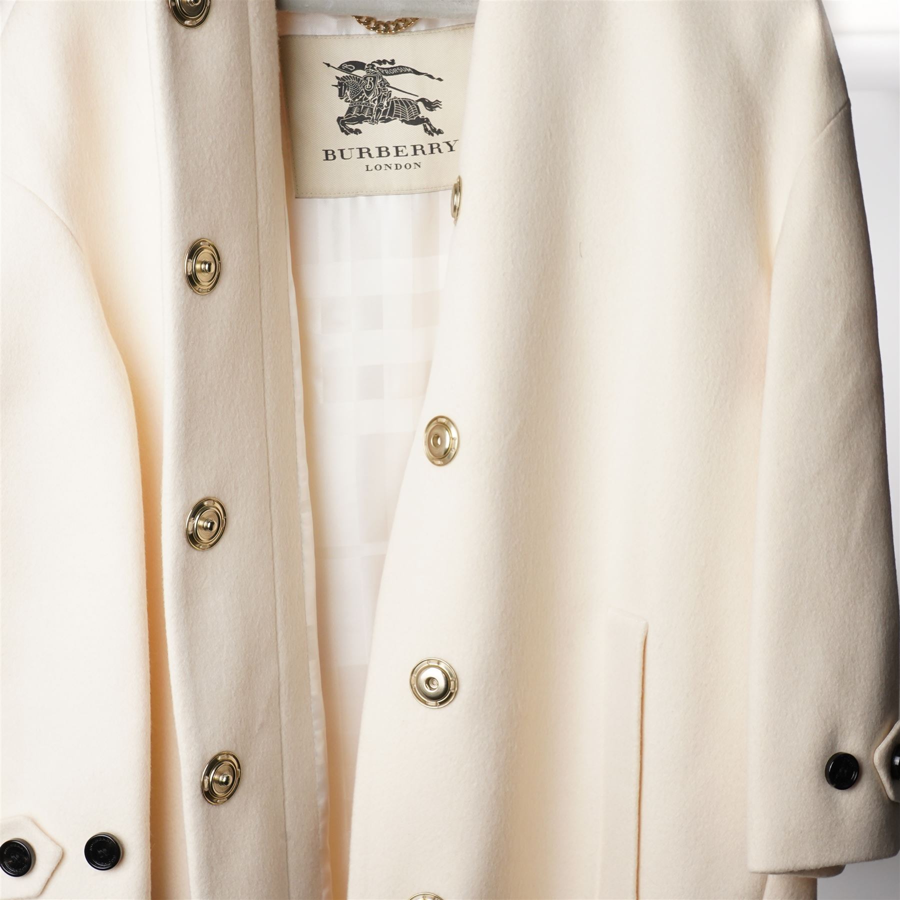 Burberry London - wool coat in cream, with concealed front popper fastening, bracelet-length sleeves with tab and black button detail and side slip pockets, with slit to back, size 40, unused with original Harvey Nichols garment bag and hanger